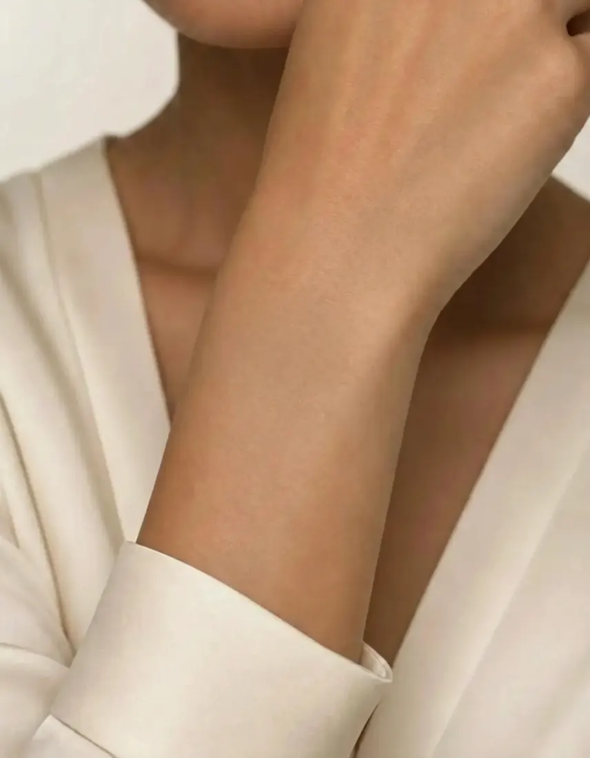 A close-up of a bare wrist in a white sleeve, before the Bracelet Generator adds jewelry.