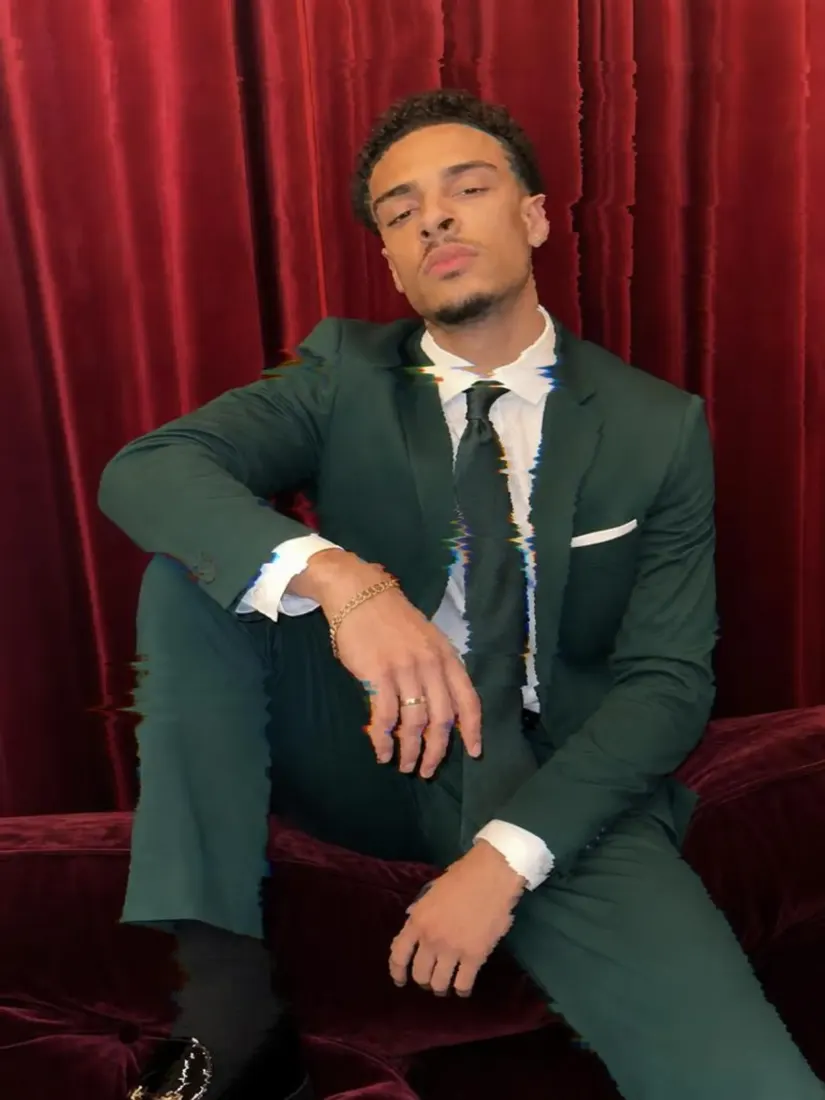 A man in a dark green suit sits against a red curtain with vertical glitch and color-split distortion, before the Distortion Remover repairs the image.