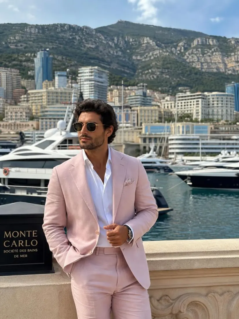 A man in a pale pink suit stands at a yacht harbor with a Monte Carlo sign visible, before the Gender Swap tool changes the portrait.