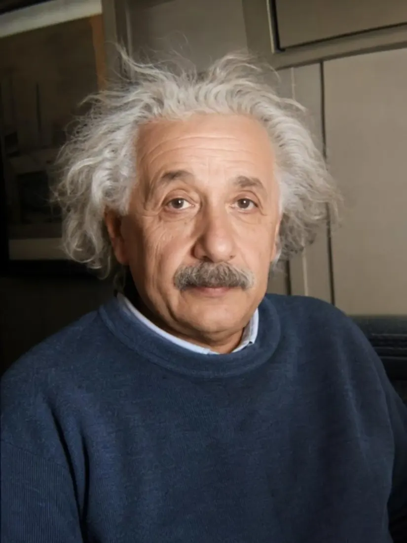 A close-up of a man with wild white hair and a mustache in a navy sweater, before the Mugshot Filter restyles the portrait.
