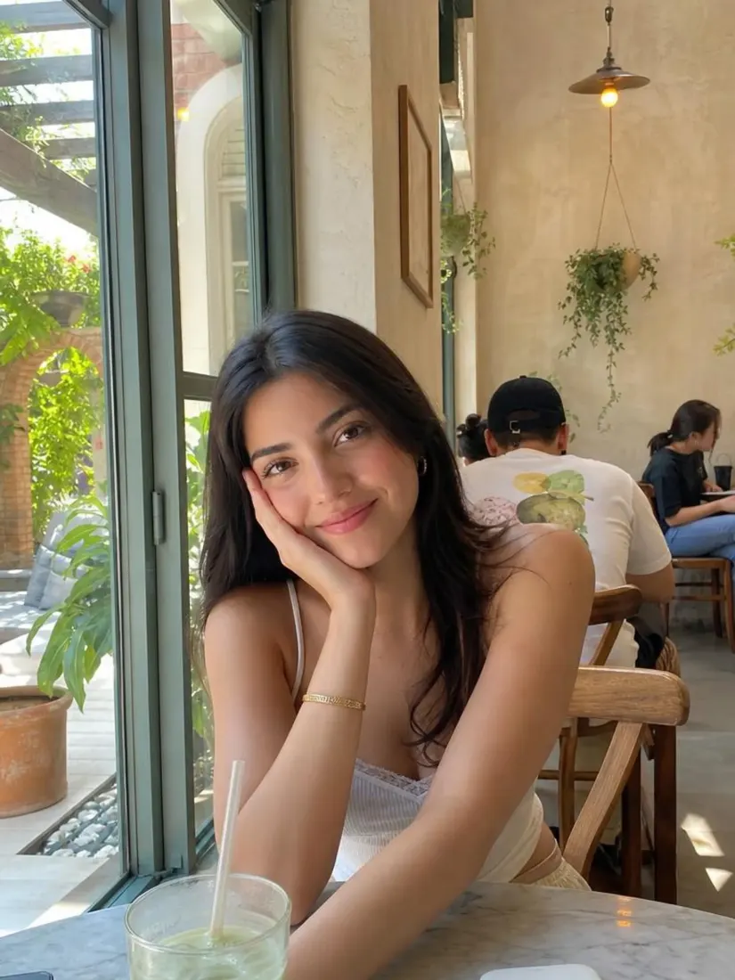 A woman resting her chin on her hand at a cafe appears sharp and clear after the Unblur Image tool.